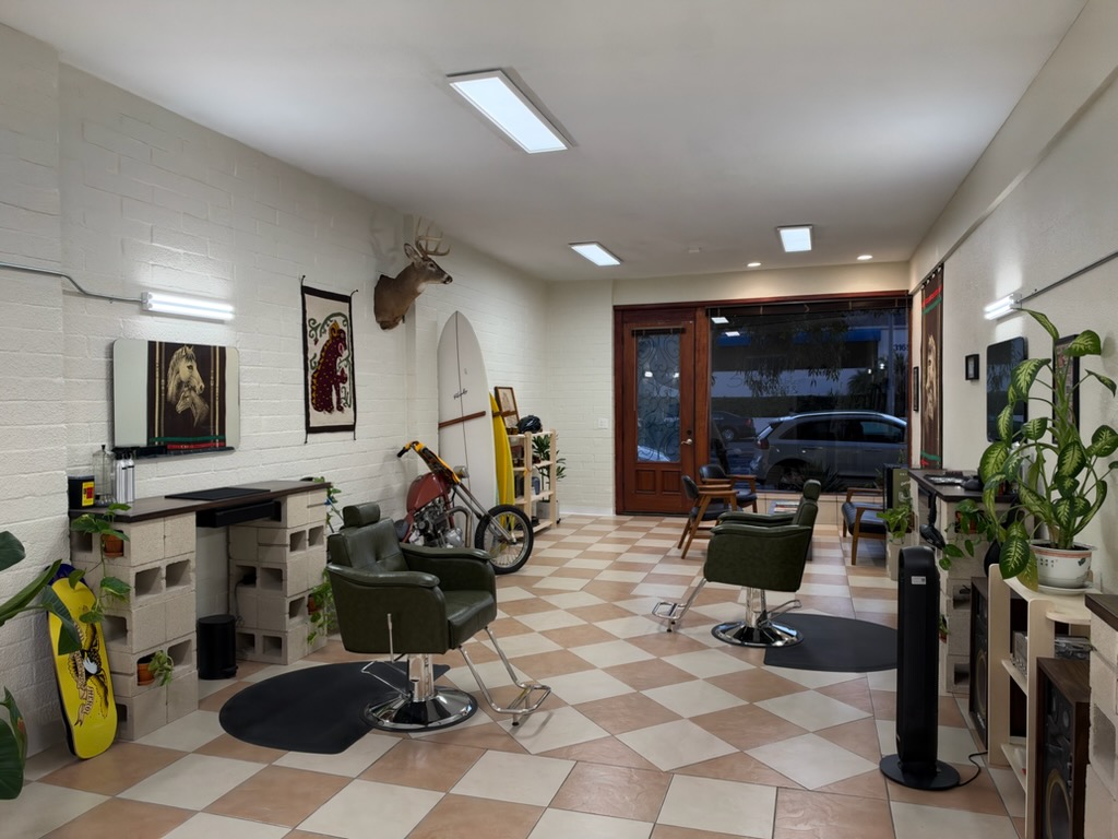 Trim Time interior with green barber chairs, a checkerboard floor, a chopper, and a surfboard