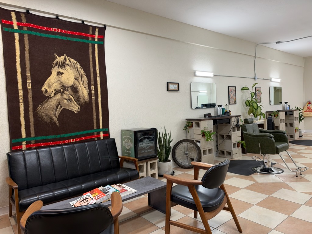 Lounge with a black leather couch, a horse blanket on the wall, and cinder block stations