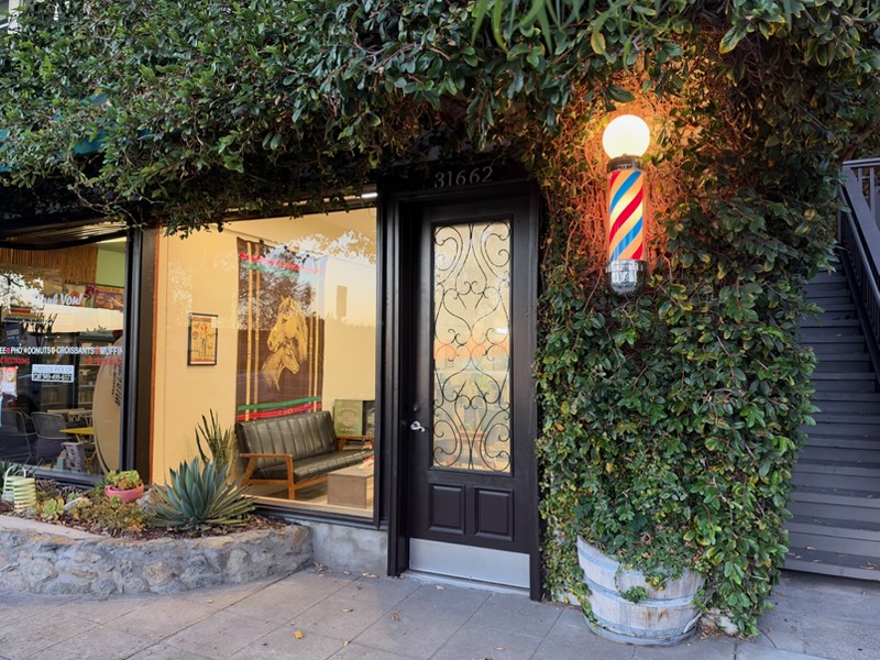 Trim Time storefront at 31662 South Coast Highway, black door, barber pole, and ivy